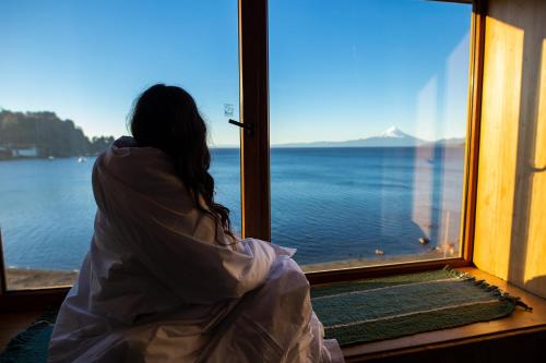 a woman sitting in front of a window looking at the water at Hotel Bellavista in Puerto Varas