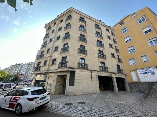 una macchina bianca parcheggiata di fronte a un edificio di Apartamento Miñoca con Garaje a Vigo