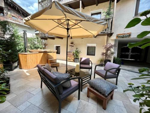 patio con tavolo, sedie e ombrellone di Maison de la montagne - Chambres & Relax ad Arvier