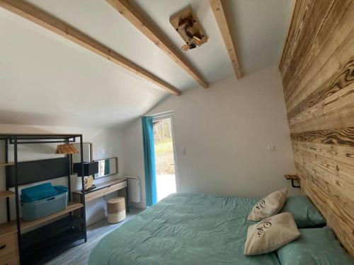sypialnia z zielonym łóżkiem i oknem w obiekcie Chalet Charmant rénové au bord du Lac St Point w mieście Montperreux