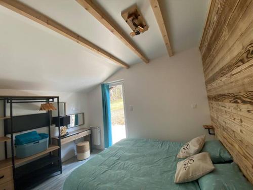 a bedroom with a green bed and a window at Chalet Charmant rénové au bord du Lac St Point in Montperreux