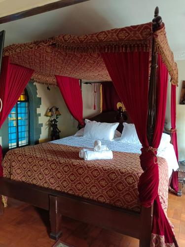 a bedroom with a canopy bed with red curtains at Castillo Medieval in Viña del Mar