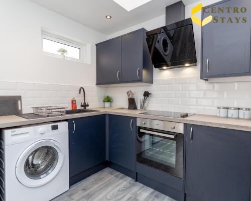 a kitchen with blue cabinets and a washer and dryer at Central 2 to 3BR House, Free Parking, Ideal for Long Stays, Work Crews & Family Trips in Northampton