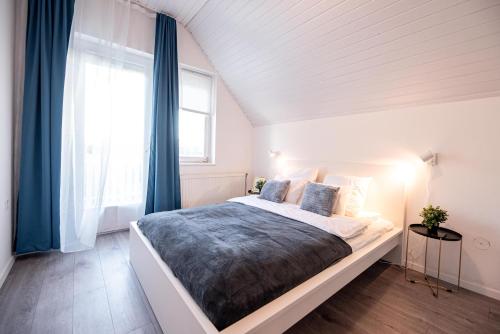 a bedroom with a bed with blue curtains and a window at Stylish Vacation Home with AC - Stílusos légkondicionált nyaraló in Siófok