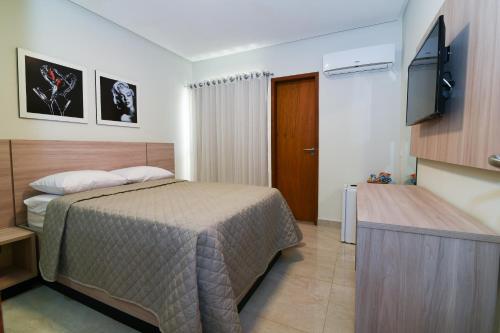 a bedroom with a bed and a flat screen tv at Star Hotel Limoeiro in Limoeiro