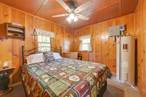 a bedroom with a bed and a refrigerator at Cozy Carp Lake Cottage with Dock, 4 Kayaks and Fire Pit in Carp Lake
