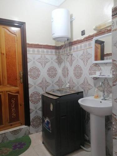 La salle de bains est pourvue d'un évier et d'un réfrigérateur noir. dans l'établissement Modern flat Dakhla, à Dakhla