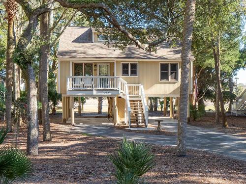 a house with a porch and a deck with trees at 545 Tarpon Pond Cottage in Seabrook Island
