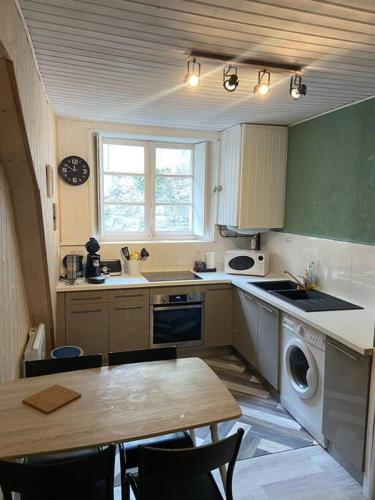 a kitchen with a table and a stove and a dishwasher at Appartement 4p Eaux-Bonnes in Eaux-Bonnes