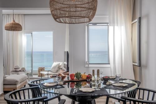 ein Esszimmer mit einem Tisch, Stühlen und Meerblick in der Unterkunft Khroma Luxury Suite 1 Beach front apartment in Hersonissos