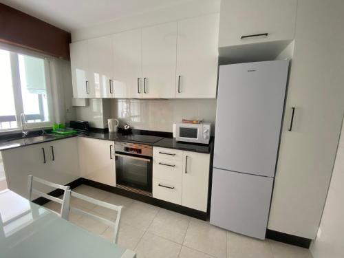 uma cozinha com armários brancos e um frigorífico branco em LALIN CENTRO URBANO, CÓMODO Y FUNCIONAL em Lalín