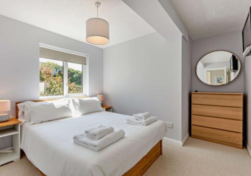 a bedroom with a large white bed with a mirror at Flat 9 Clifton Court in Croyde