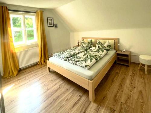 a bedroom with a bed with a wooden floor and a window at Lendorfer Cottage in Feldkirchen in Kärnten
