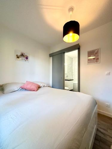 une chambre avec un grand lit blanc avec une lampe dans l'établissement Aux portes de Strasbourg, à Mundolsheim