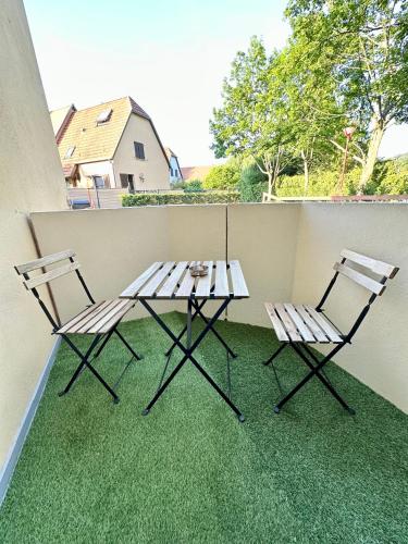Duas cadeiras e uma mesa numa varanda com relva em Aux portes de Strasbourg em Mundolsheim