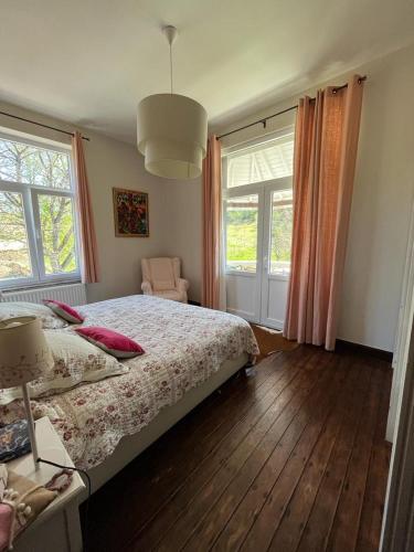 a bedroom with a bed and a chair and windows at Les 3 Soeurs in Han-sur-Lesse