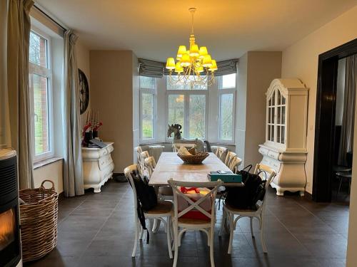 a dining room with a table and chairs and a chandelier at Les 3 Soeurs in Han-sur-Lesse