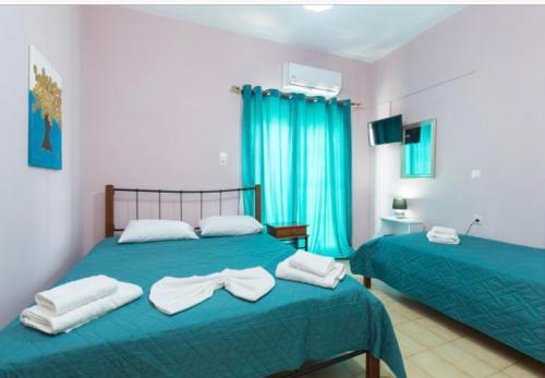 two beds in a bedroom with blue curtains and towels at Eleni in Kissamos