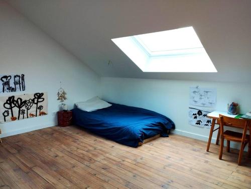 - une chambre avec un lit bleu et une lucarne dans l'établissement Maison avec jardin au calme, à Nantes