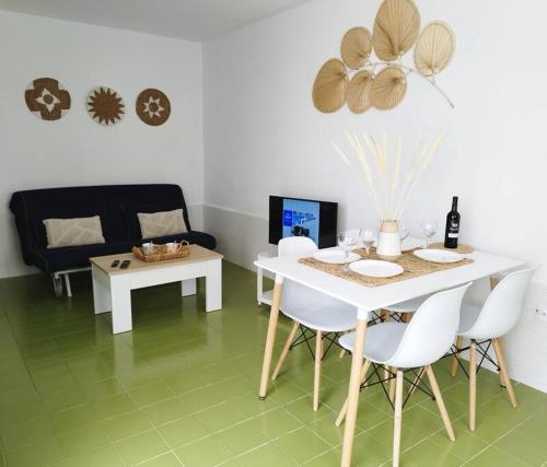 a living room with a white table and white chairs at Charmant Appartement Casa Freesia Caleta avec piscine in Caleta De Fuste