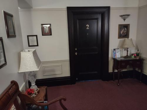 a room with a black door and a table and a lamp at The King George Inn in Cobourg