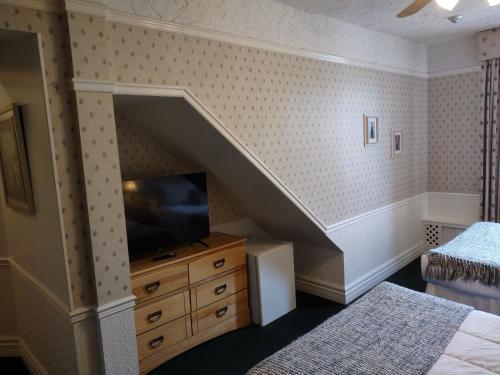 a bedroom with a staircase with a tv and a dresser at The King George Inn in Cobourg