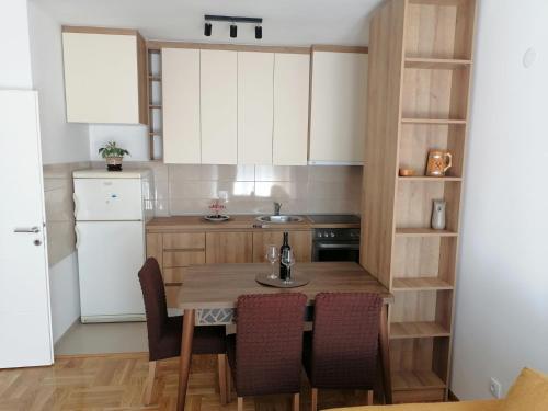 eine Küche mit einem Tisch mit Stühlen und einem Kühlschrank in der Unterkunft Apartman Nomino in Zvornik