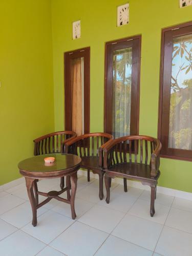 three chairs and a table in a room with green walls at Berlian Inn Kuta Beach in Kuta