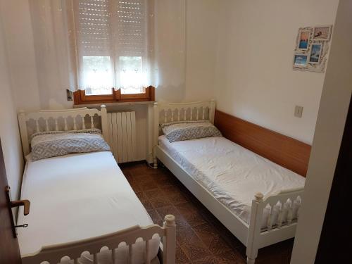 two beds in a small room with two windows at Flavia Flats in Bibione