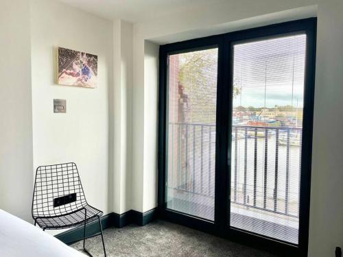 a room with a bed and a window with a chair at Duplex Apartment Harbourside city centre in Bristol