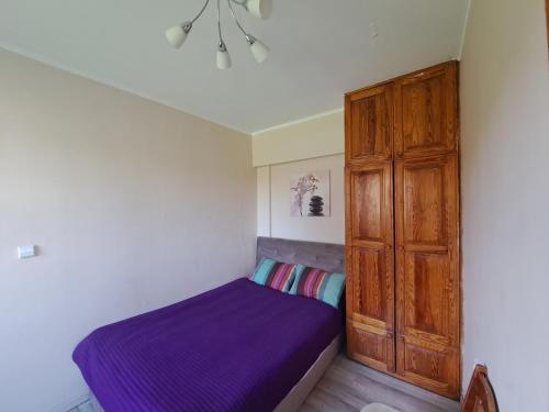 1 dormitorio con cama morada y armario de madera en Erdvus butas su privačiu įėjimu J. Vienožinskio 56, en Kaunas