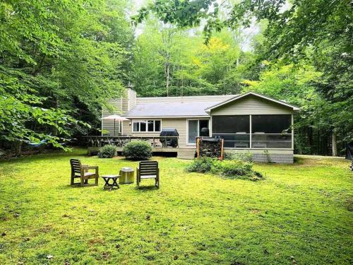 a house with a yard with chairs and a table at The Monk's Cottage-White Mountains, Pet Friendly in Woodstock