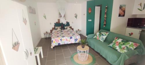 sala de estar con cama y sofá verde en Studio MADRAS AVEC PISCINE ET SPA A 5 MN DE LA MER, en Saint-François