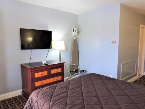 1 dormitorio con 1 cama, TV y vestidor en Windsor Motel en Groton