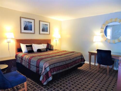 a hotel room with a bed and a table and a mirror at Windsor Motel in Groton