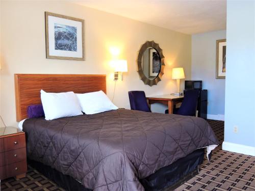Cette chambre comprend un lit et un bureau. dans l'établissement Windsor Motel, à Groton