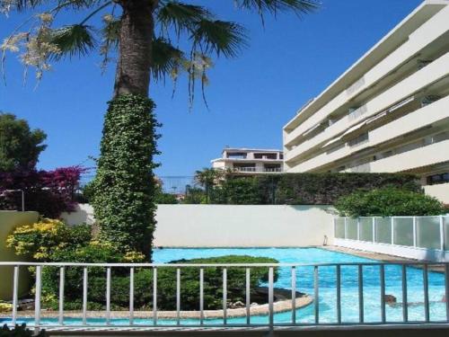 - une piscine en face d'un bâtiment avec un palmier dans l'établissement Studio cosy à 30 mètres de la plage, à Antibes