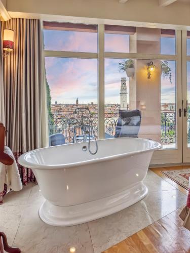 a bath tub in a room with a large window at Relais Colle San Pietro in Verona