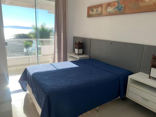 1 dormitorio con cama azul y ventana grande en Res. Signus, en Bombinhas
