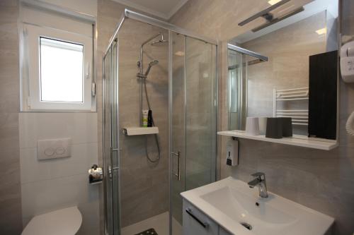 ein Bad mit einer Dusche und einem Waschbecken in der Unterkunft Apartmani Ive in Trogir