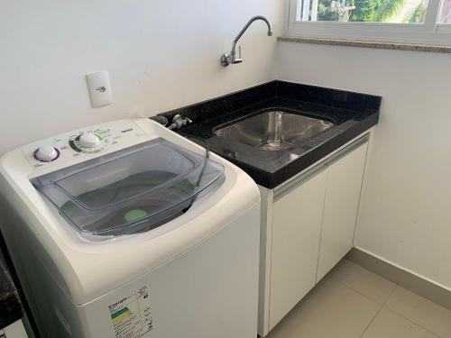 a kitchen with a sink and a washing machine at Res. Signus in Bombinhas
