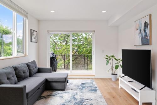 a living room with a couch and a flat screen tv at Modern two story townhouse near light rail in Seattle