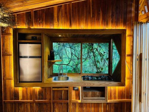 a kitchen with a window in a wooden wall at Tamarindo Pura Selva Eco Tree House in Guatemala