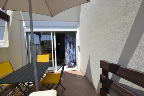 a balcony with a table and chairs and an umbrella at Studio Naturiste "JUL'S"Port Nature 401 in Cap d'Agde