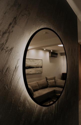 a mirror on a wall with a couch in a room at Apartman Pelagić in Brčko