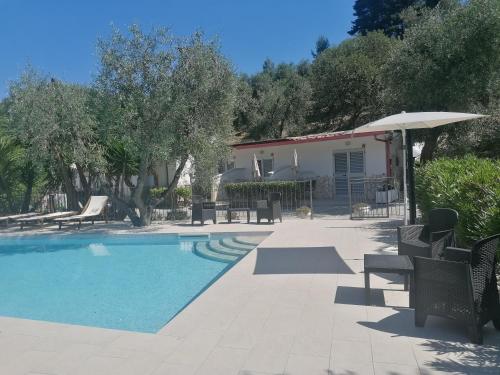 ペスキチにあるAgriturismo Valle Dei Gelsiの家の隣に椅子とパラソル付きのプールがあります。