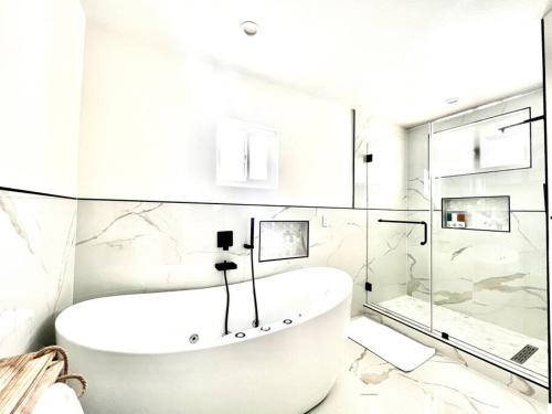 a white bathroom with a tub and a shower at Luxury 5BR-Salt Pool- Disney, Convention, Beaches in Tustin