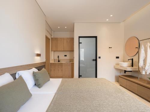 a bedroom with a large white bed and a bathroom at Esperides Beach Hotel Apartments in Stalos