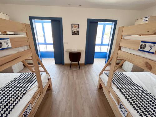 a room with three bunk beds and a desk at O Refuxio do Náufrago in Camelle