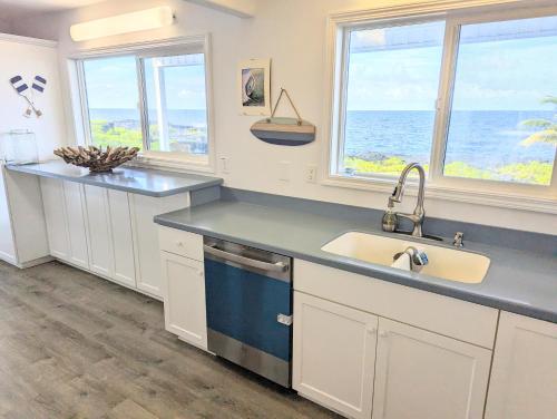 a kitchen with a sink and two windows at Maka'Ala Lani - A view of Heaven in Keaau